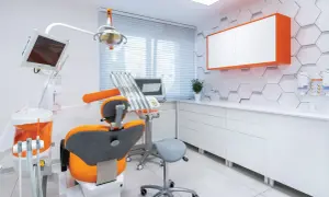 Nowoczesny gabinet stomatologiczny z fotelem i sprzętem.