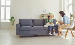 Dziewczynka z misiem siedzi na kanapie naprzeciwko psychoterapeutki.