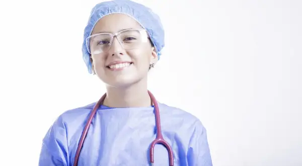 Uśmiechnięta lekarka w czepku i okularach, z różowym stetoskopem. Szukasz najlepszych klinik medycyny estetycznej we Wrocławiu?