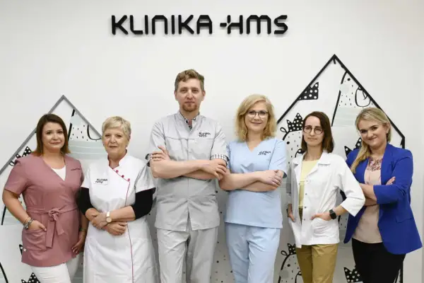 Zespół medyczny w klinice, sześć osób w uniformach medycznych, na tle logo kliniki.